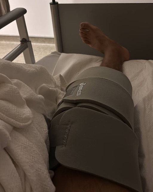 A leg in a knee brace, resting in bed